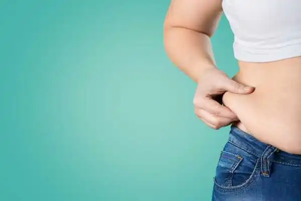 Image of woman pinching her love handles to show weight gain Peterborough